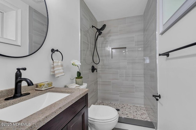 full bath featuring tiled shower, toilet, and vanity