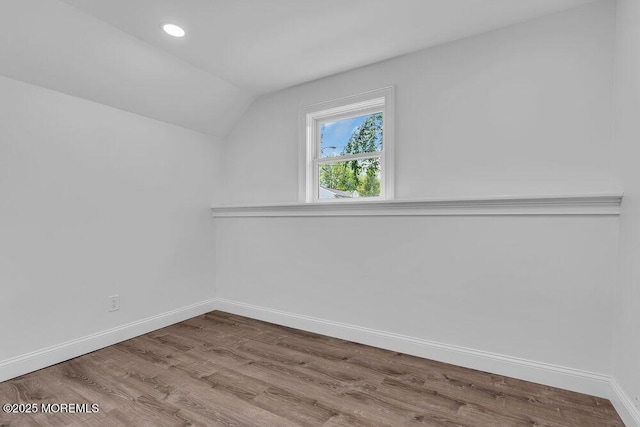 additional living space featuring vaulted ceiling, baseboards, wood finished floors, and recessed lighting