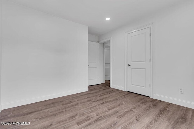 unfurnished bedroom with wood finished floors, baseboards, and recessed lighting