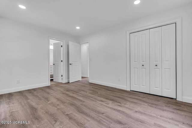 unfurnished bedroom featuring baseboards, wood finished floors, recessed lighting, a closet, and connected bathroom