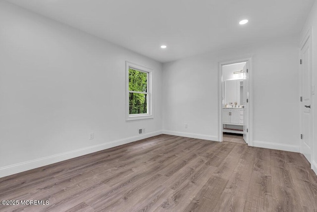 unfurnished bedroom with wood finished floors, recessed lighting, baseboards, and ensuite bath