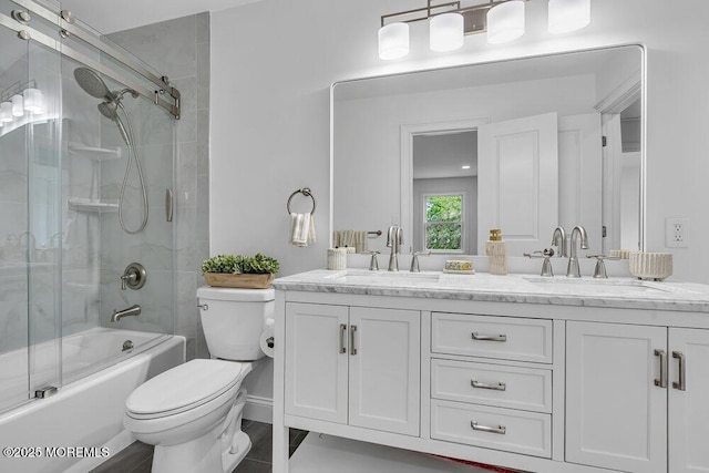 bathroom featuring toilet, double vanity, and bath / shower combo with glass door