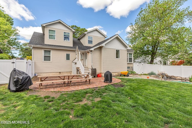 back of property with a gate, a patio, and roof with shingles