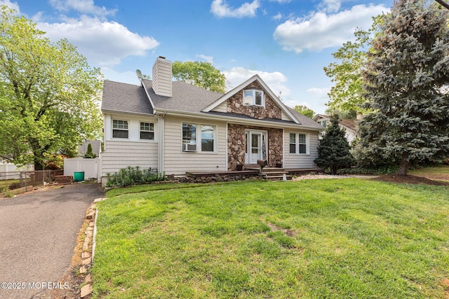 view of front of property with a chimney, stone siding, roof with shingles, and asphalt driveway