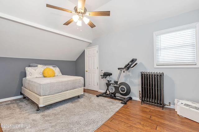 bedroom with radiator heating unit, vaulted ceiling, hardwood / wood-style flooring, a ceiling fan, and baseboards