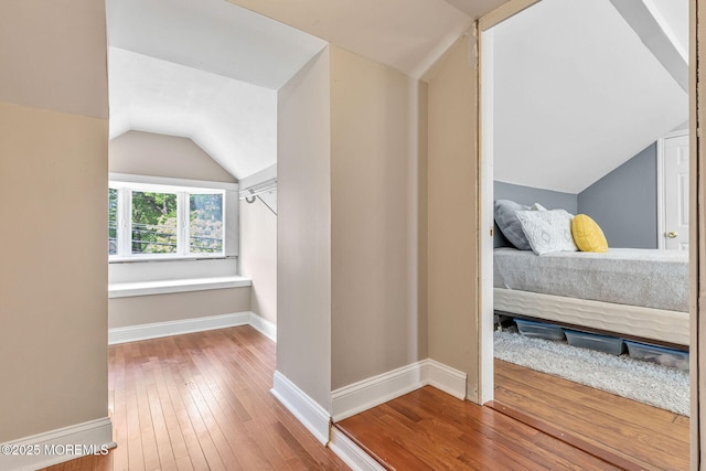 unfurnished bedroom featuring lofted ceiling, hardwood / wood-style flooring, and baseboards
