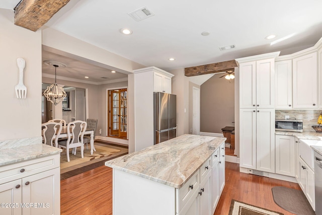 kitchen with stainless steel appliances, light wood finished floors, white cabinets, a chandelier, and light stone counters