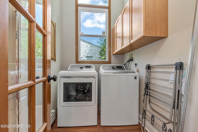 clothes washing area with cabinet space, washer and dryer, and wood finished floors