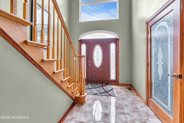 entrance foyer with a high ceiling, stairway, marble finish floors, and baseboards
