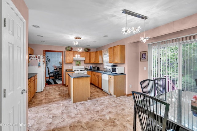 kitchen with white appliances, a chandelier, dark countertops, a center island, and under cabinet range hood