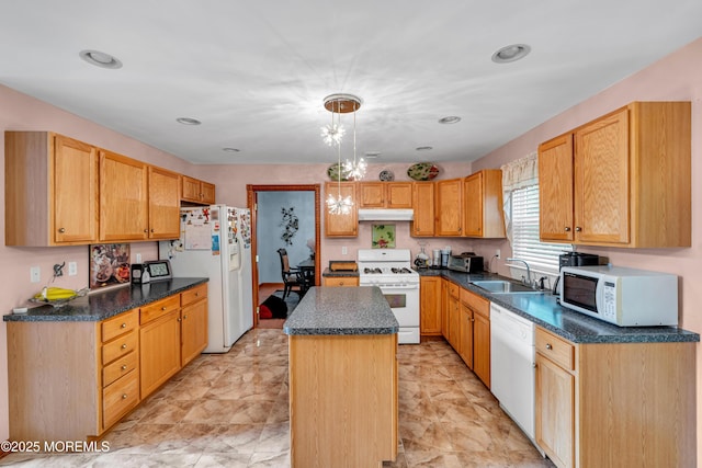 kitchen featuring white appliances, a sink, under cabinet range hood, a center island, and pendant lighting