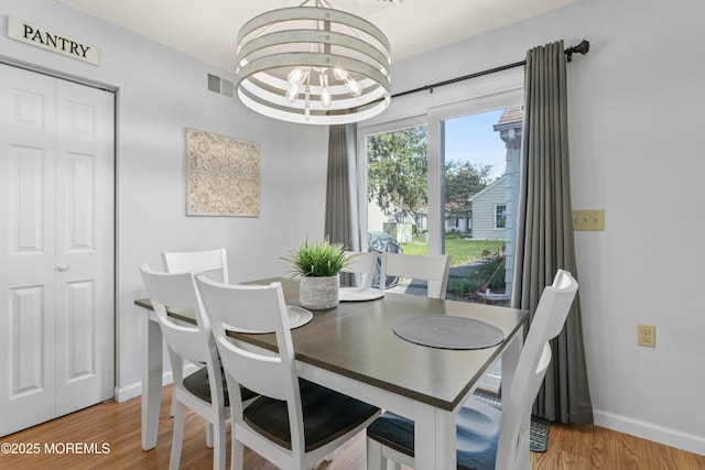 dining area with a chandelier, baseboards, and wood finished floors