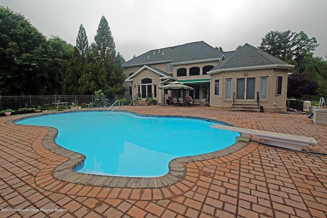 view of swimming pool with a patio area, fence, a diving board, and entry steps