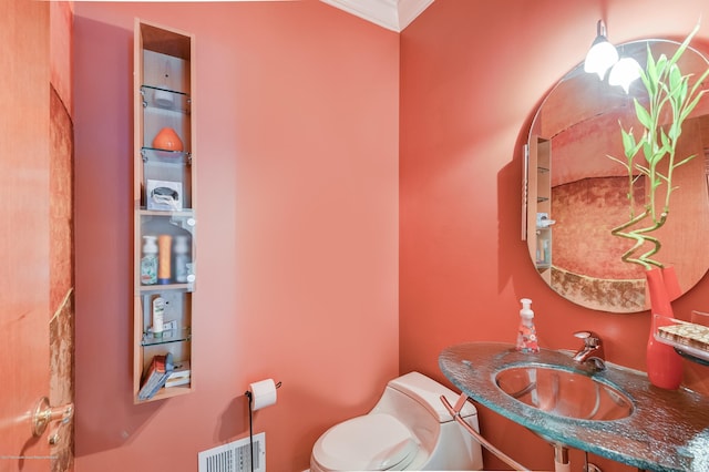 half bathroom featuring a sink, toilet, and ornamental molding
