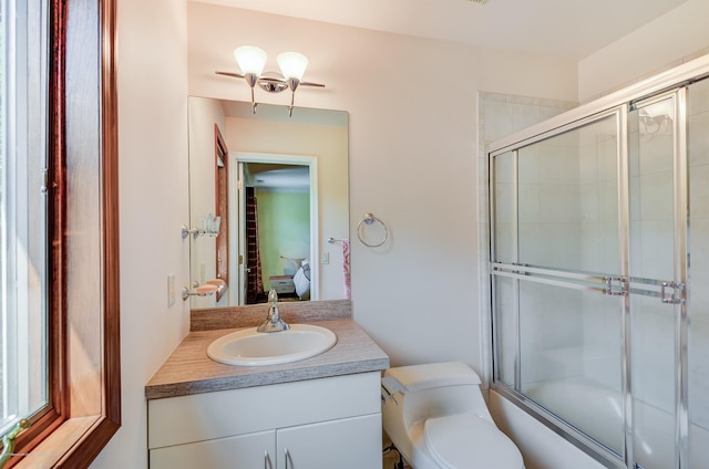 full bath with connected bathroom, vanity, toilet, and enclosed tub / shower combo
