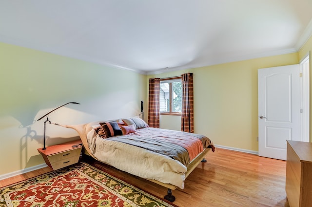 bedroom with crown molding, light wood-type flooring, and baseboards