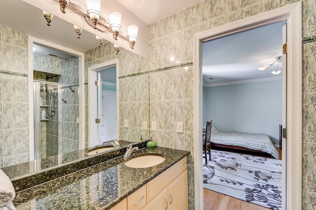 ensuite bathroom featuring a stall shower, tile walls, wood finished floors, crown molding, and vanity