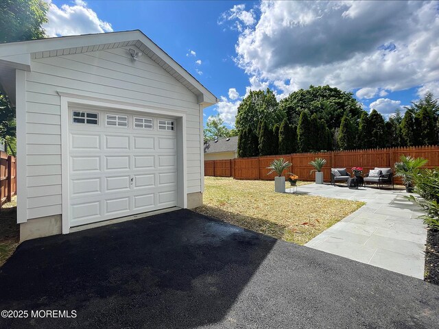 garage featuring fence and asphalt driveway
