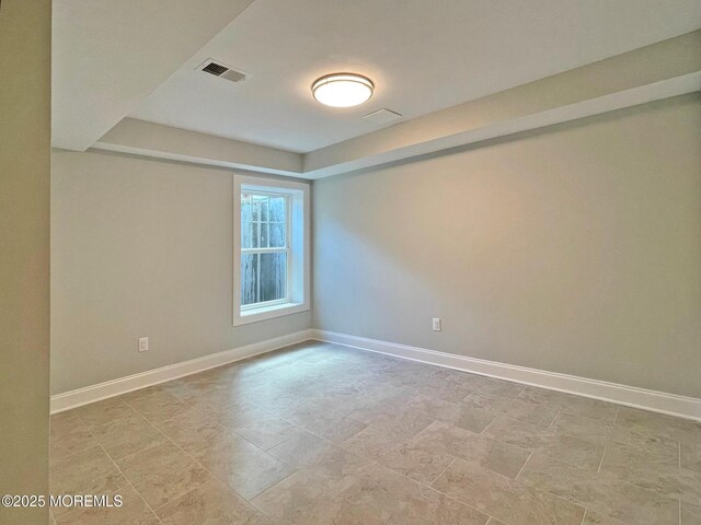 spare room featuring baseboards and a raised ceiling
