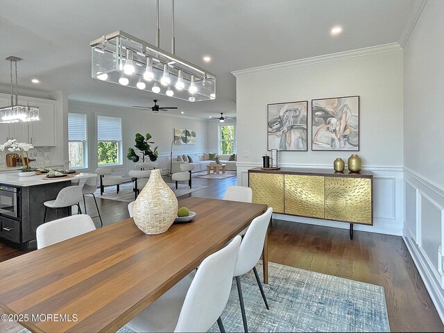 dining area featuring ornamental molding, a ceiling fan, dark wood-type flooring, a wainscoted wall, and recessed lighting