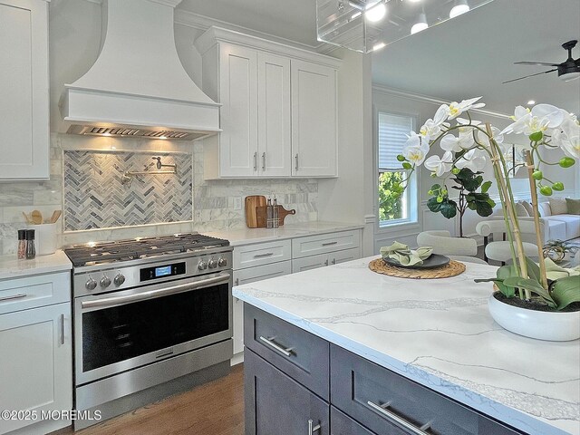 kitchen with gas stove, premium range hood, white cabinets, dark wood-style floors, and tasteful backsplash