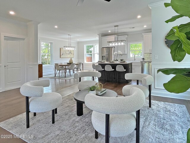 living room with wood finished floors, crown molding, recessed lighting, and a chandelier