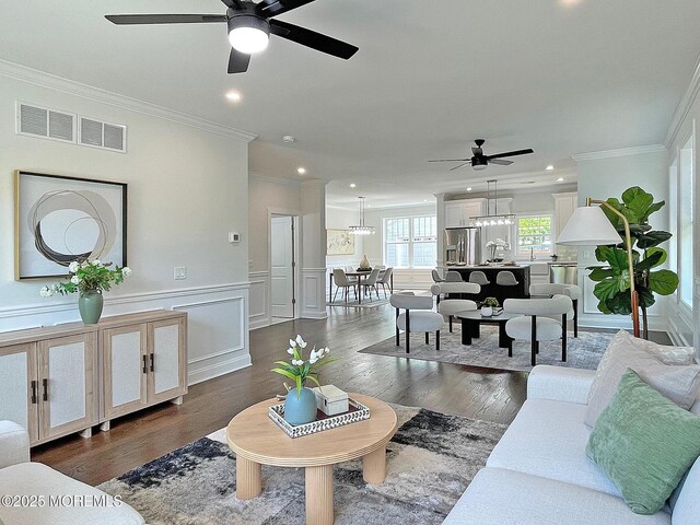 living room featuring ceiling fan, ornamental molding, dark wood-type flooring, recessed lighting, and a chandelier