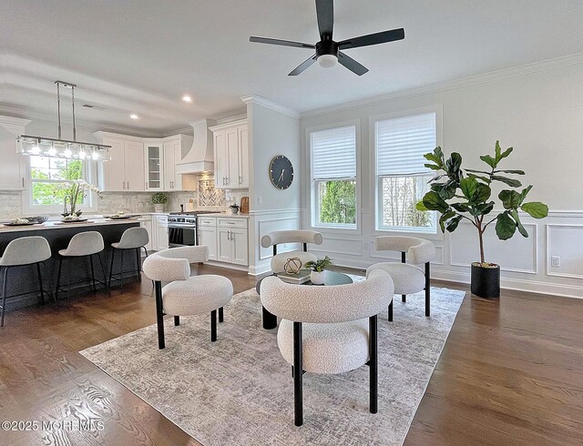living area with ornamental molding, a decorative wall, a ceiling fan, dark wood finished floors, and recessed lighting