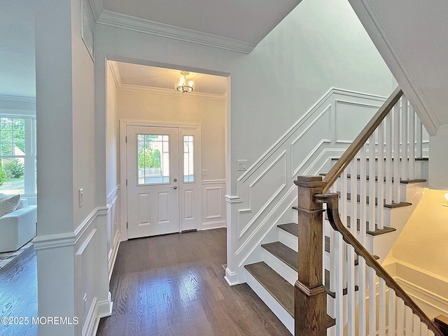 entryway with a decorative wall, crown molding, stairs, dark wood-style floors, and a wainscoted wall