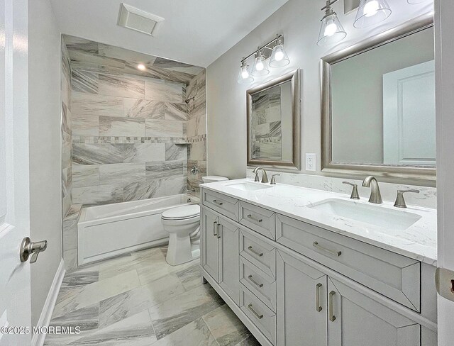 bathroom with toilet, double vanity, washtub / shower combination, marble look tile flooring, and baseboards