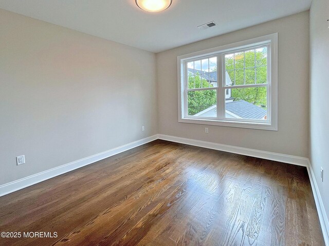 unfurnished room with baseboards and dark wood-style floors