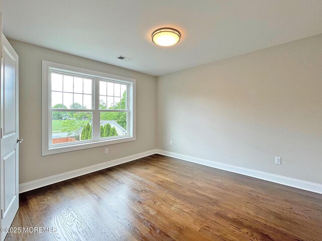 spare room with dark wood-style flooring and baseboards