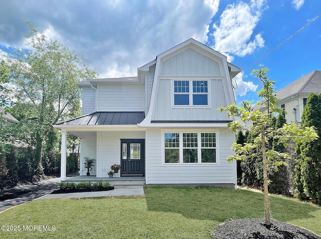 view of front of house with a standing seam roof, covered porch, a front lawn, metal roof, and board and batten siding