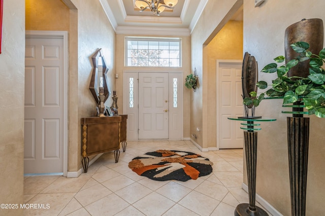 foyer featuring ornamental molding, a chandelier, light tile patterned flooring, baseboards, and a tray ceiling