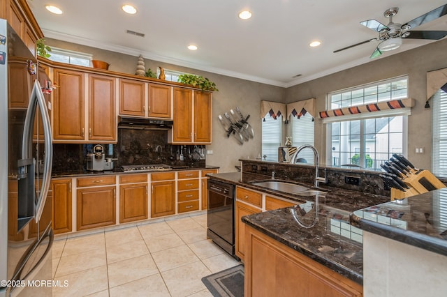 kitchen with appliances with stainless steel finishes, a sink, a ceiling fan, brown cabinetry, and under cabinet range hood