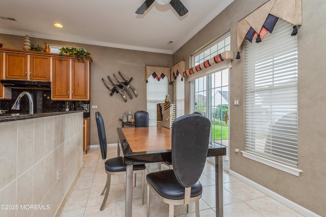 dining room with light tile patterned floors, ornamental molding, ceiling fan, and baseboards