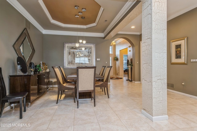 dining space with arched walkways, a tray ceiling, light tile patterned floors, ornamental molding, and baseboards