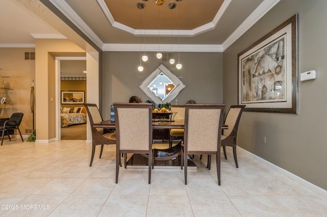 dining room featuring a tray ceiling, light tile patterned floors, crown molding, and baseboards