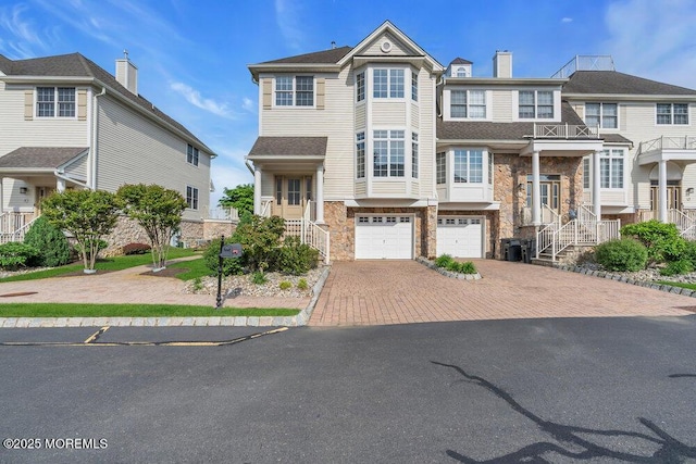 townhome / multi-family property featuring stone siding, decorative driveway, and a garage