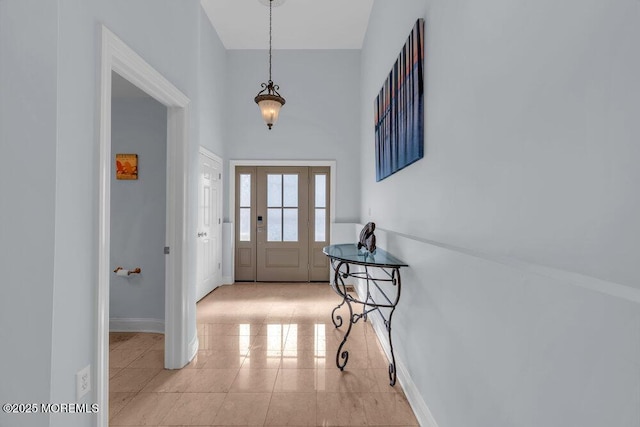 entryway featuring baseboards, light tile patterned flooring, and a high ceiling