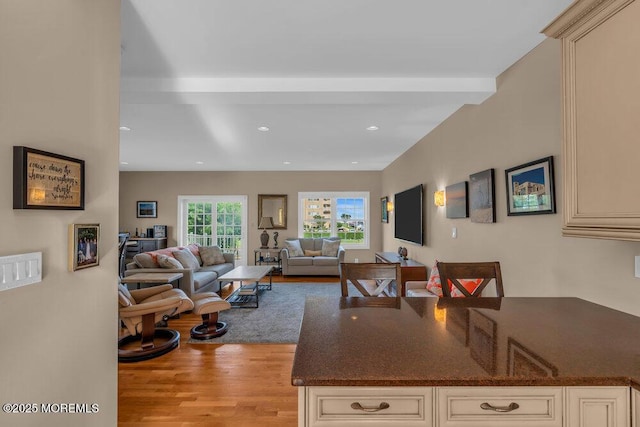 kitchen with cream cabinetry, light wood-type flooring, recessed lighting, open floor plan, and dark stone countertops