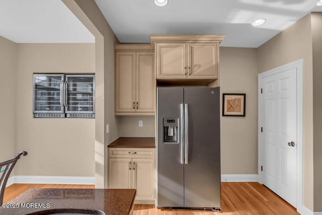 kitchen with stainless steel fridge with ice dispenser, light wood-style flooring, baseboards, dark countertops, and recessed lighting