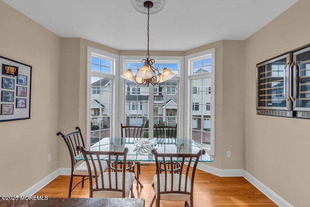 dining area featuring healthy amount of natural light, wood finished floors, and a chandelier