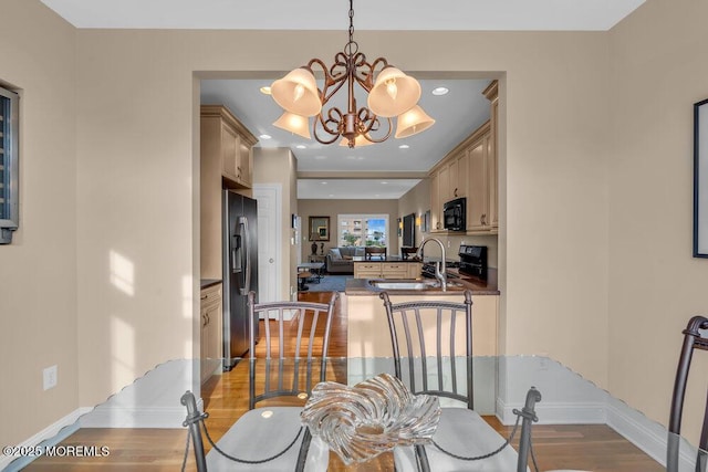 dining space featuring light wood-style floors, a chandelier, baseboards, and recessed lighting
