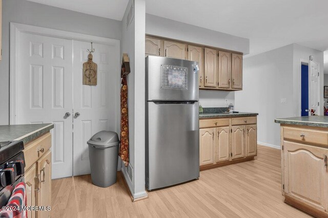 kitchen featuring freestanding refrigerator, dark countertops, and light wood-style floors