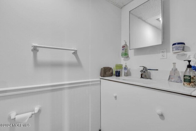 bathroom with a paneled ceiling, vanity, and wainscoting