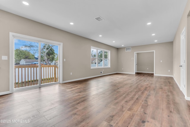 spare room with plenty of natural light, wood finished floors, recessed lighting, and baseboards