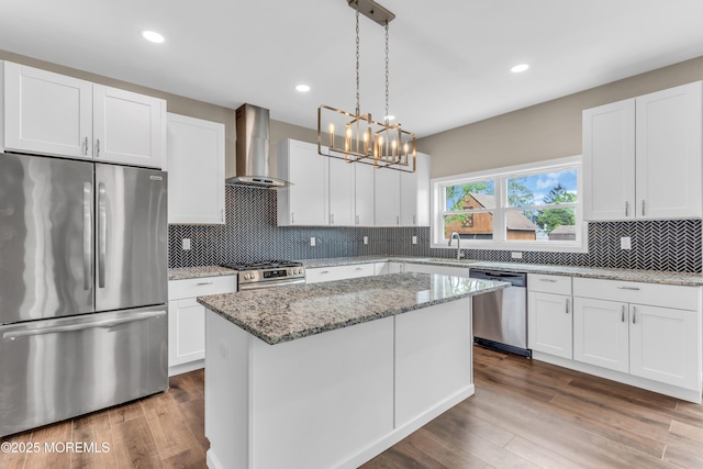kitchen with stainless steel appliances, wall chimney range hood, white cabinetry, a kitchen island, and recessed lighting