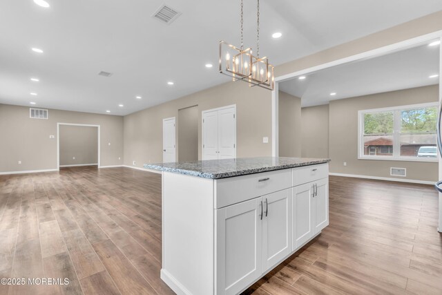 kitchen with open floor plan, light wood-style floors, a center island, white cabinets, and recessed lighting