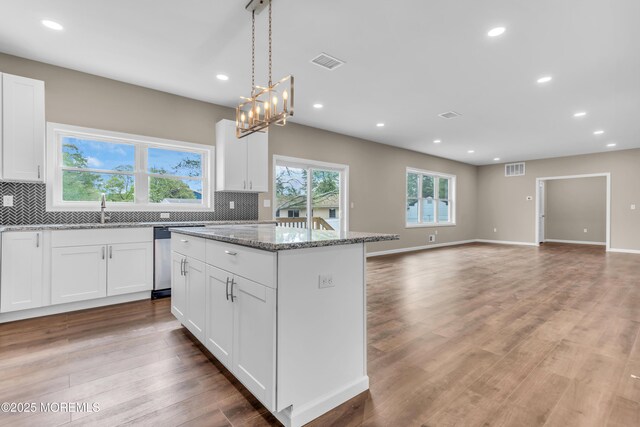 kitchen with a kitchen island, decorative backsplash, recessed lighting, white cabinets, and light stone countertops